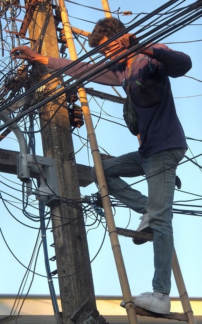 Young man climbing on electric pole, Chiang Mai, Thailand